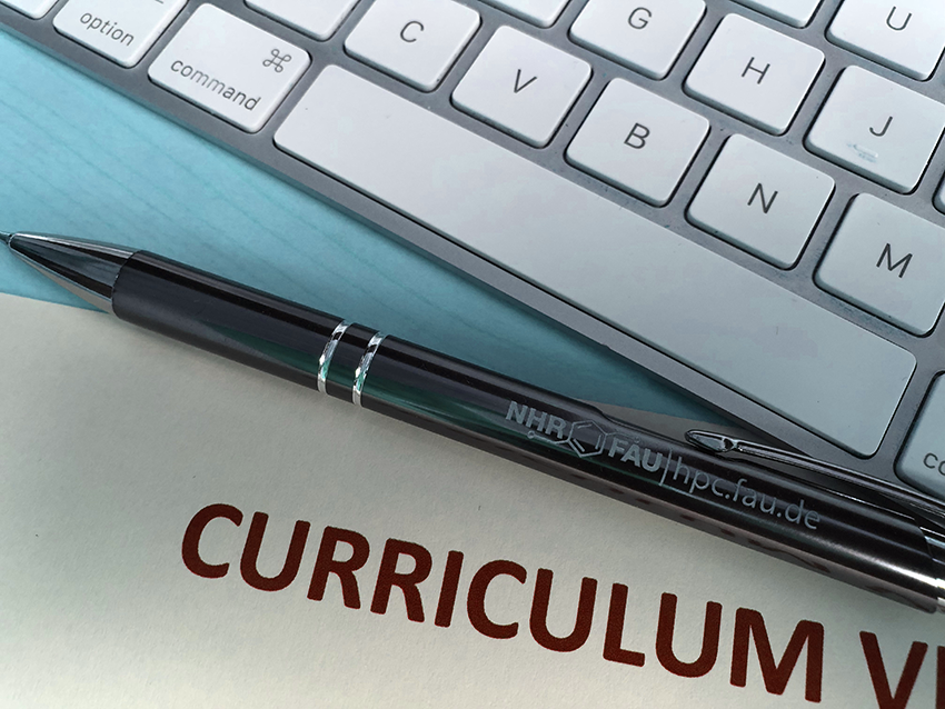 The image shows a cutout of a keyboard, a ballpoint pen with the NHR@FAU logo, and a cutout of the head of a resume.