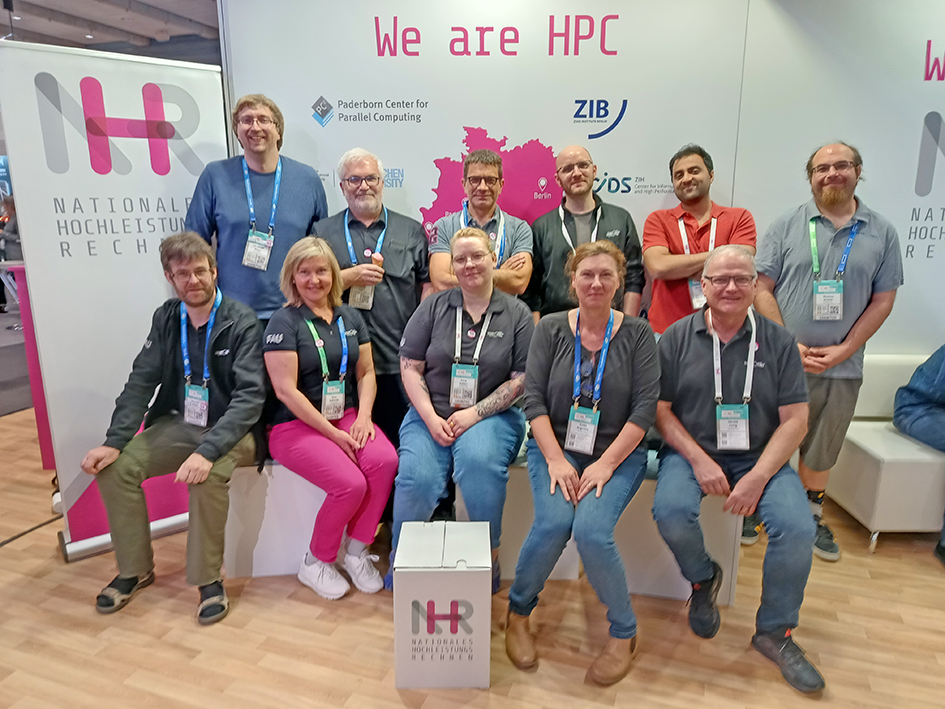 A group of employees from the NHR@FAU in front of their conference booth.