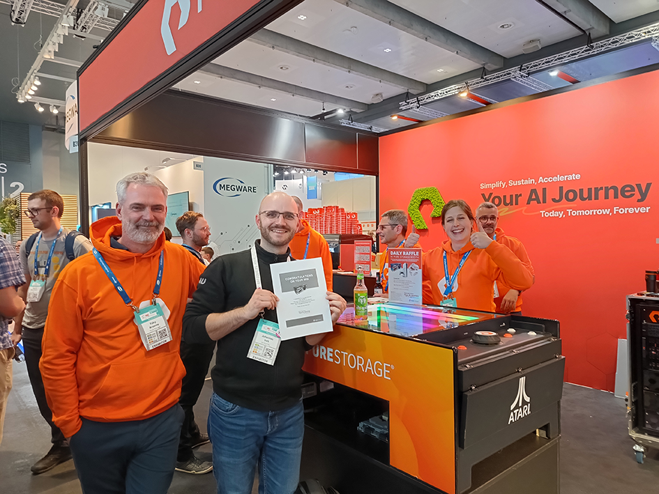 Two Nhr@FAU researchers in front of the booth of the company 