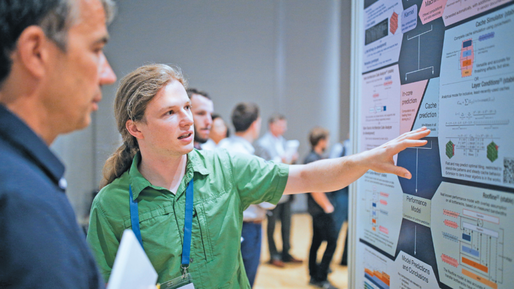 A researcher pointing at a display with a scientific poster explaining the content to a man next to him.