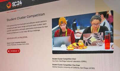 The website of the SC24 cluster competition on a screen with a photo of two female students on their laptops.