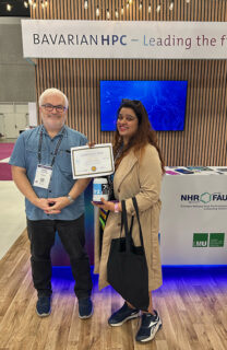 Georg Hager handing obver the second prize in the HPC and computer history quiz, an LRZ beer mug, to Manikya Swathi Vallabhajosyula from Ohio State University (Image: S. Schulte, LRZ)